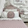 Łóżko przykryw aksamitną pikowaną narzutą w kolorze pastelowego różu , ozdobione dekoracyjnymi poduszkami ozdobnymi.