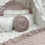 Łóżko przykryw aksamitną pikowaną narzutą w kolorze pastelowego różu , ozdobione dekoracyjnymi poduszkami ozdobnymi.
