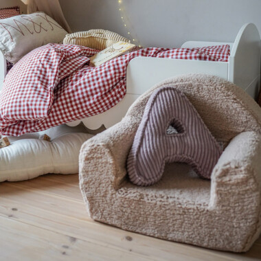 Zdjęcie dziecięcego fotelika wykonanego z wysokiej jakości pianki, pokrytego miękką futrzaną tkaniną, z boczną kieszonką na drobiazgi.