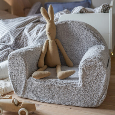 Zdjęcie wygodnego fotelika dziecięcego wykonanego z wysokiej jakości pianki, pokrytego futrzaną tkaniną, z boczną kieszonką na drobiazgi.